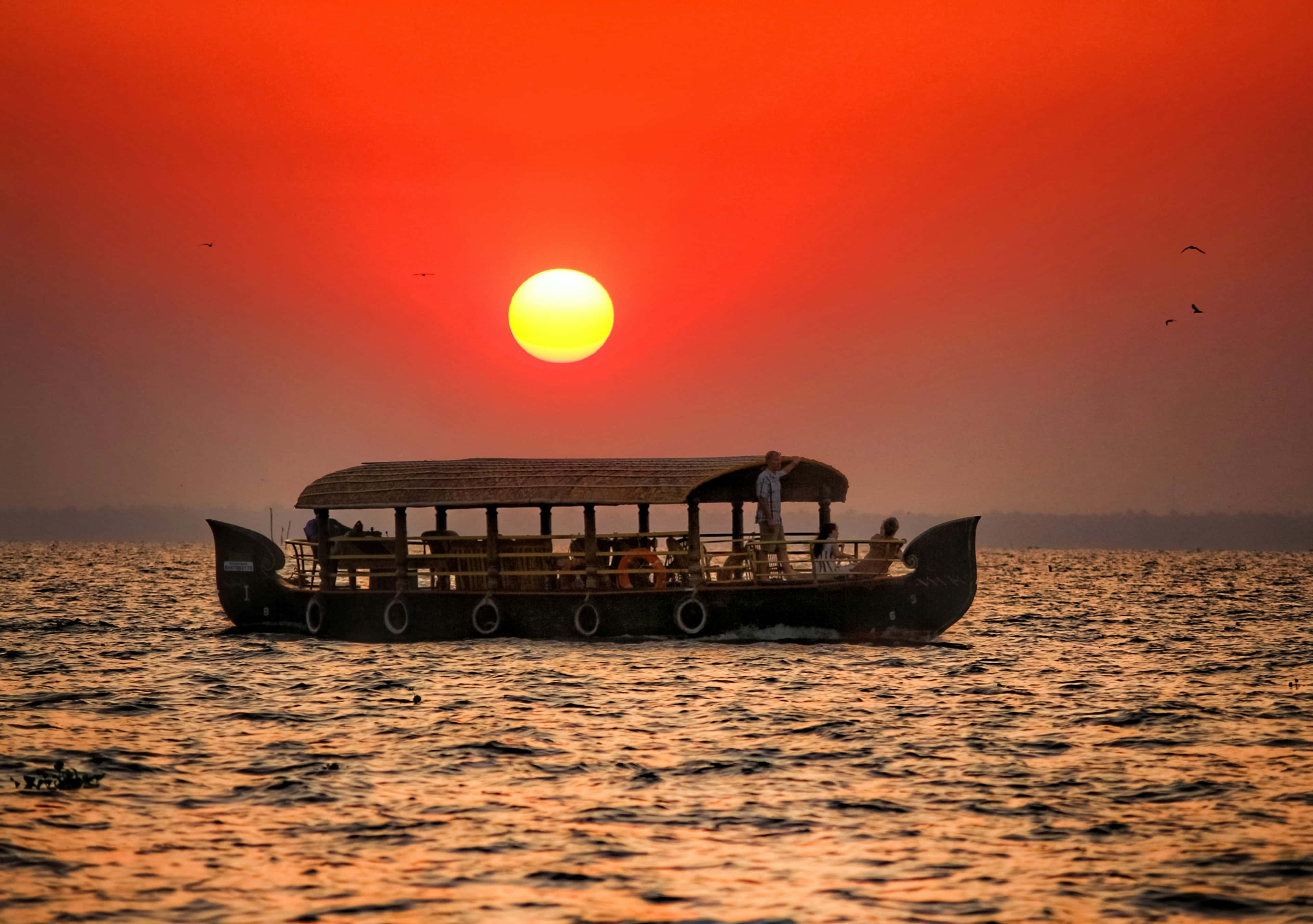 Kerala houseboat silhouetted against a red sunset