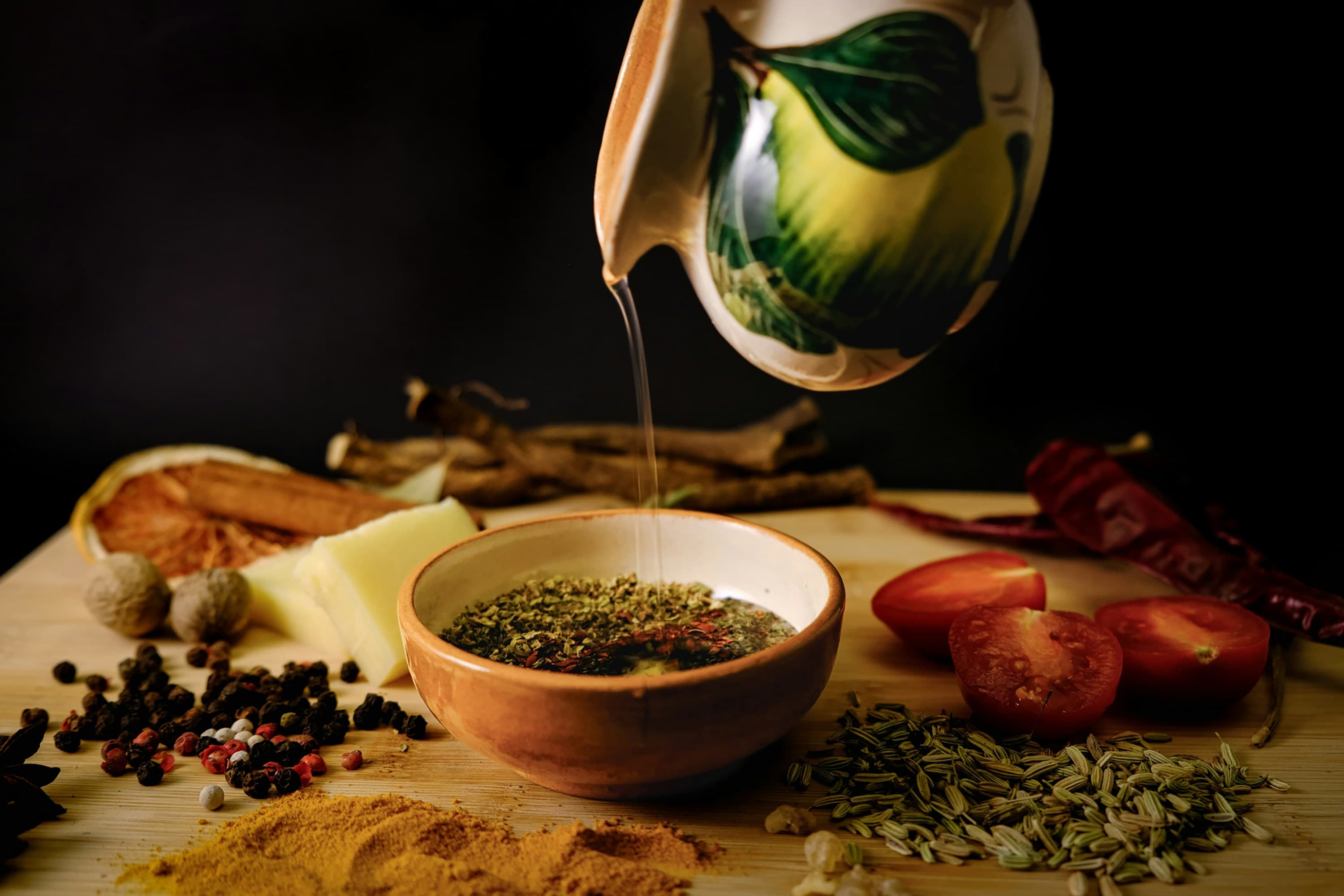 Oil poured over a bowl of fresh herbs